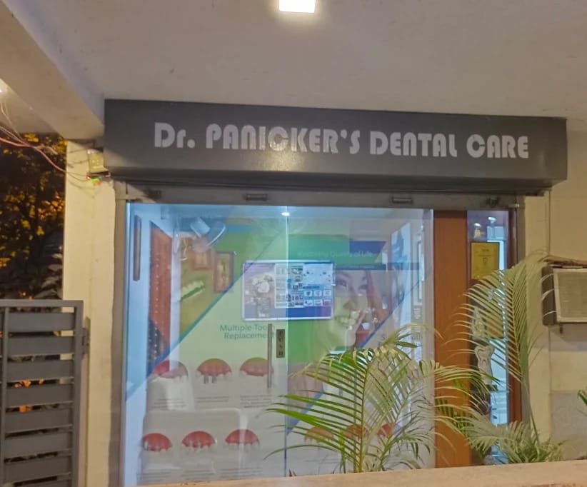 Glass entrance of Dr Panicker's Dental Care lit up in the evening